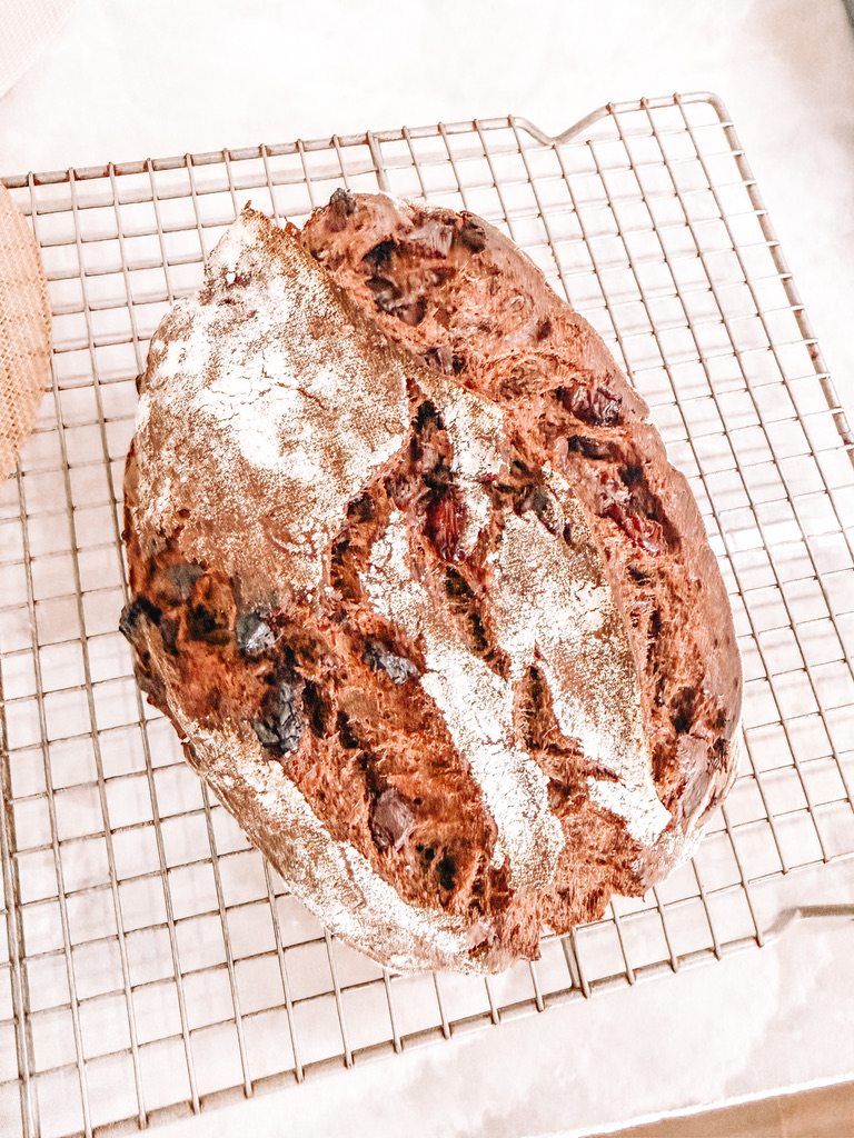 A dark chocolate cherry sourdough loaf on a cooling rack