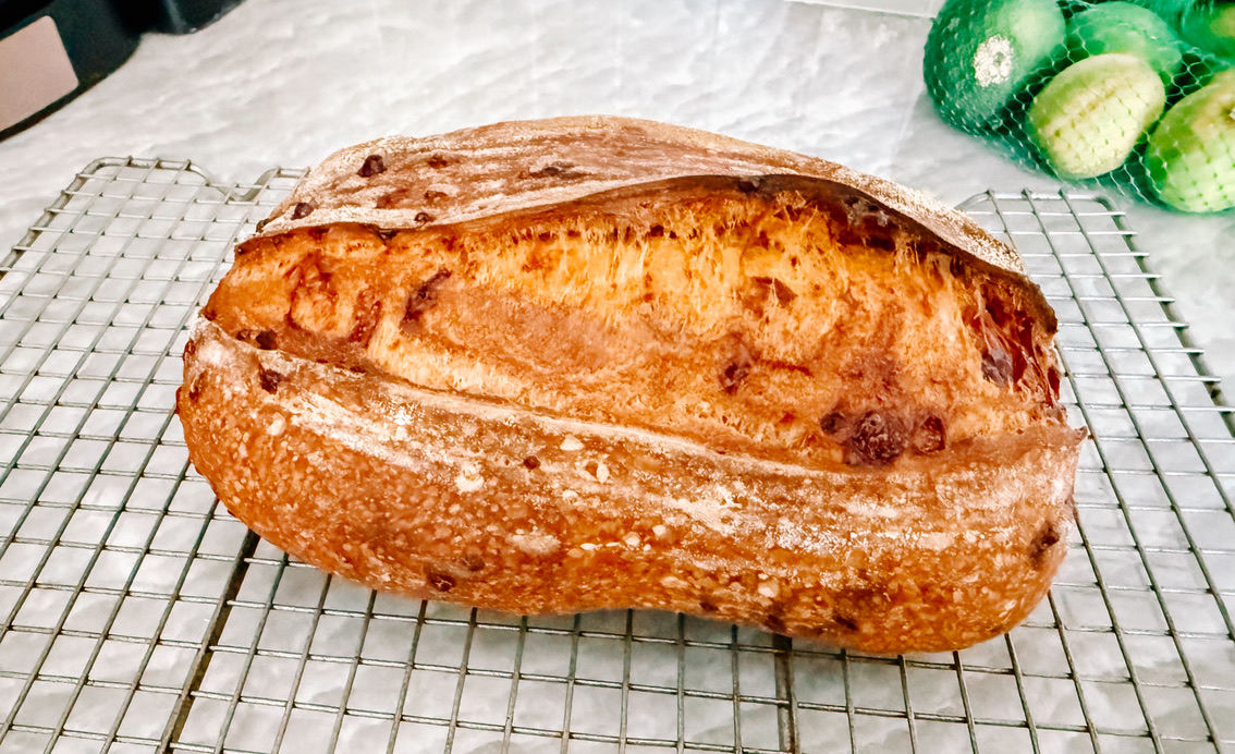 A golden Casa Dos Osos house sourdough loaf cooling on a wire rack